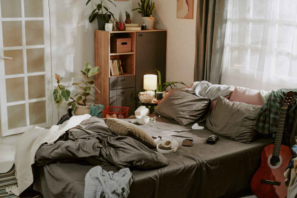 Quarto desorganizado com cama bagunçada e objetos espalhados, ilustrando a ideia de que a falta de organização interfere no descanso e na tranquilidade mental.