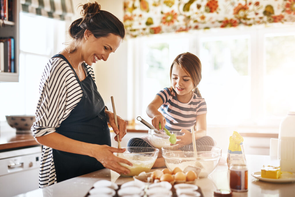 Mãe e filha na cozinha cozinhando em tom de harmonia e colaboração
